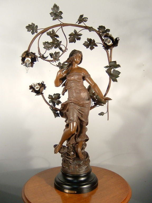 French figural newel post style lamp, made of spelter, has been fully restored. Lovely figure of a woman with flowing robes, with a bird perched at her feet, surrounded by vines and foliage holding 3 candelabra bulb sockets. Marked on the base with