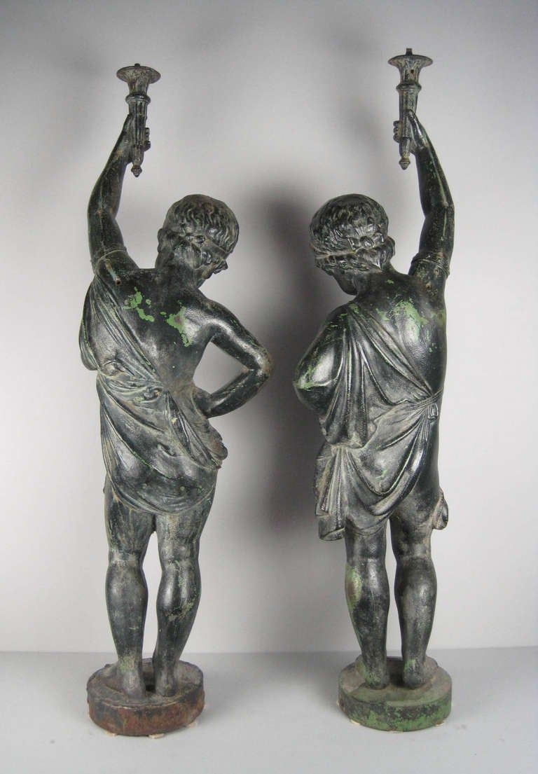Ca. 19th Century A pair of 19th Century cast iron cupid figures. Two separate castings marked ‘Antoine Durenne’ of Sommevoire, France. Both figures take on a sultry and confident stance as they each hold a torchiere.
Excellent condition with