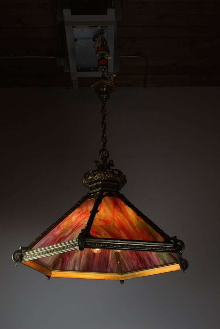 An absolutely stunning Tiffany style pendant in the style of Italian Renaissance Revival, circa 1910. This six sided pendant featuring delicious rhubarb coloured glass, with rich green and sumptuous orchid tones. This piece absolutely comes alive