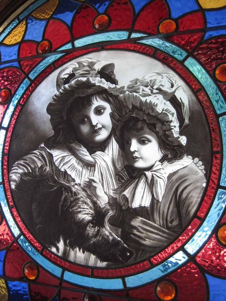 Ca. 1885 Unique stained glass window of exceptional quality. Unusual spun and pressed blue and red jewels decorate the intricate full-colour leaded glass panels which encompass a hand-painted portrait of two young women with a dog. An outstanding