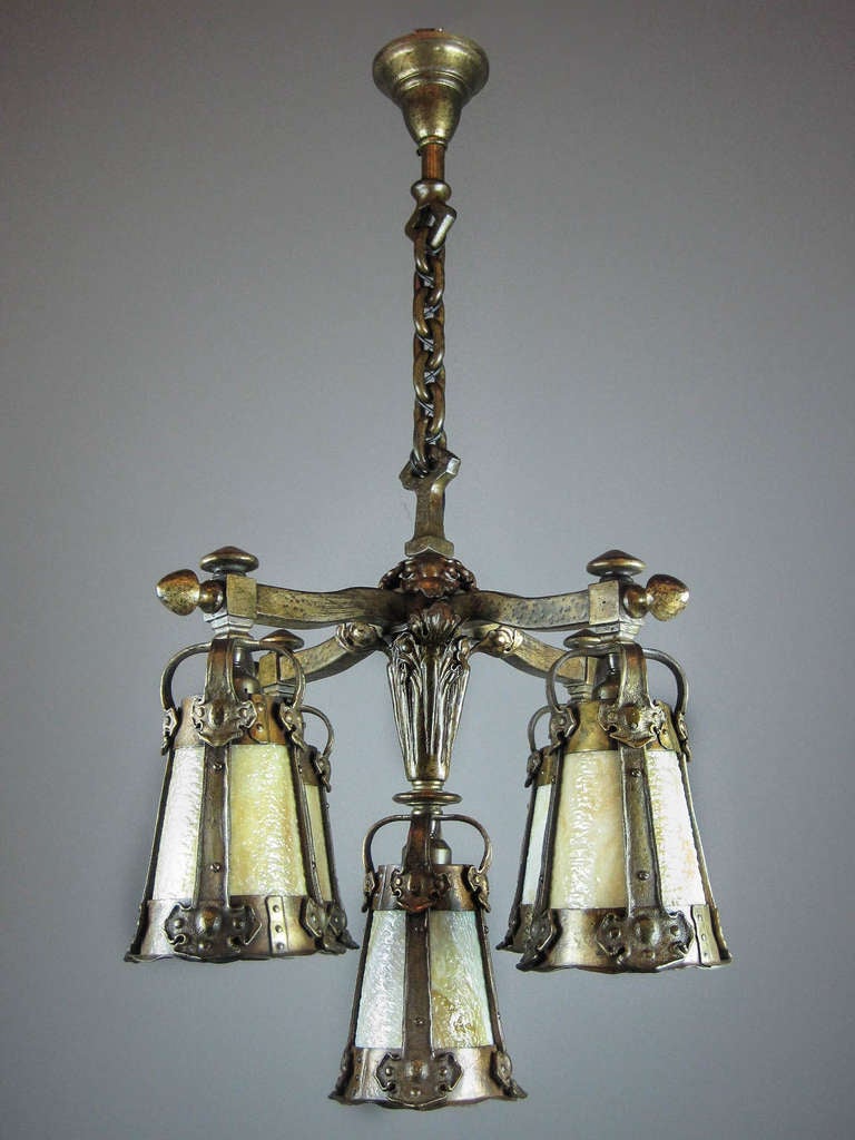 Ca. 1912 Arts & Crafts fixture with slag glass shades. This 5-light fixture is completely original with matching canopy and chain. Note the unusual Gothic-style decorations and center shade.
Measurements: 29