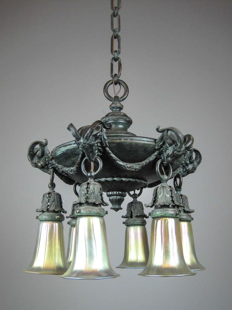 Ca. 1915 Attributed to ‘Miller & Co.’ this figural light fixture is of the highest quality with original ‘Verdigris’ finish.
The body is adorned with a profusely cast ‘Rams Head’ and swag motif along with matching stylized chain and shade