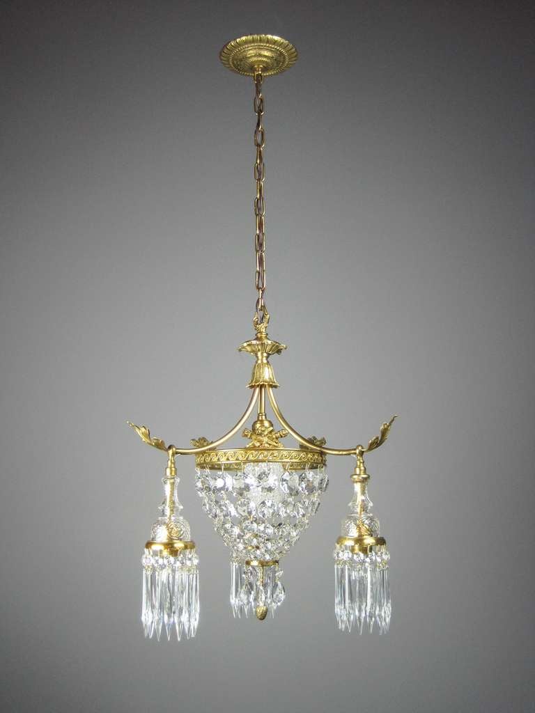 Ca. 1912 Crystal French Empire basket light fixture made of brass with a true antique gold plated finish. Attributed to Moran & Hastings (Chicago). Decorative ring is embellished with whimsical pattern and crossed sword motif.Each arm has a