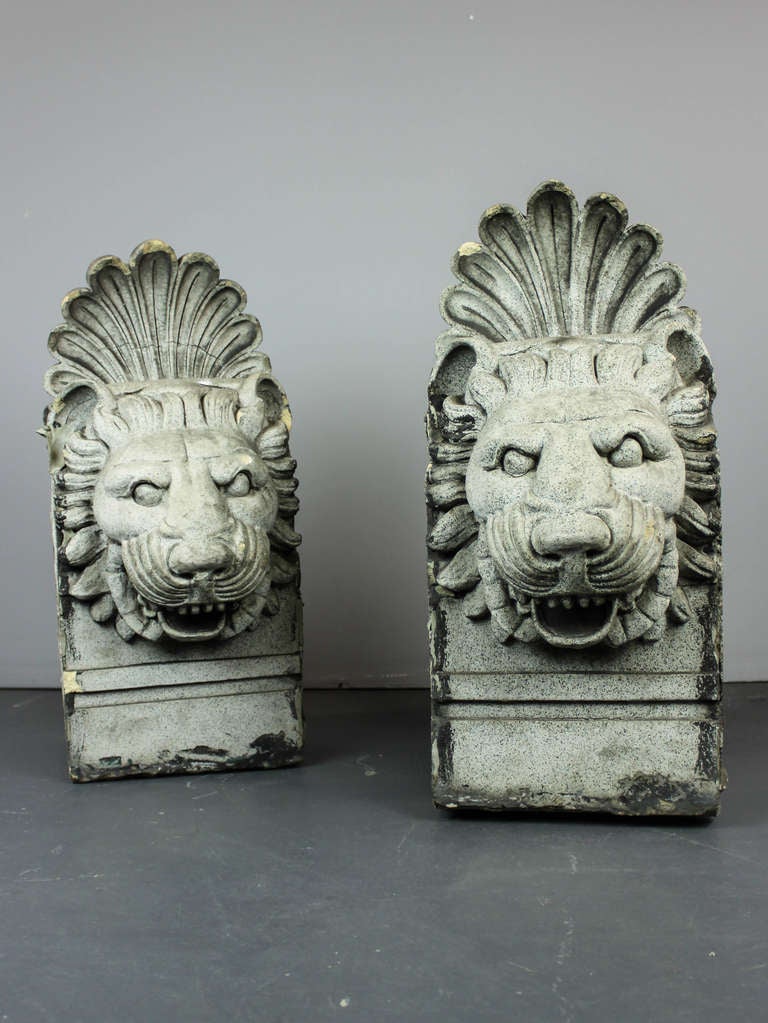 Ca. 1920 Pair of terra cotta lion heads, architectural remnants form the exterior of a building decorated building. The faces are stylized with a strong gaze, decorated with a swept mane and large acanthus flourish.
Measurements: 26