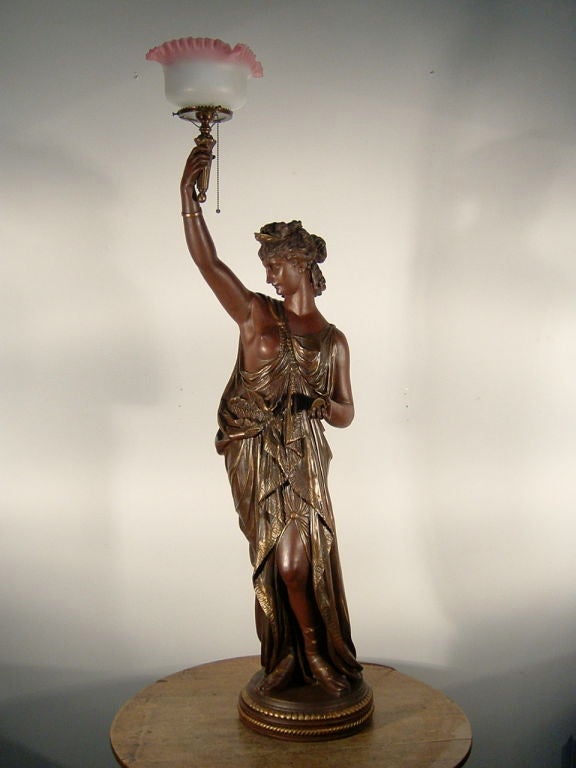 Bronzed spelter lady newel post lamp, attributed to 'Mitchell Vance'. Note the gold coin in her hand signifying finance; this type of figure was popularized in the 3rd quarter of the 19th century, often found in banks and hotels. Fitted with an