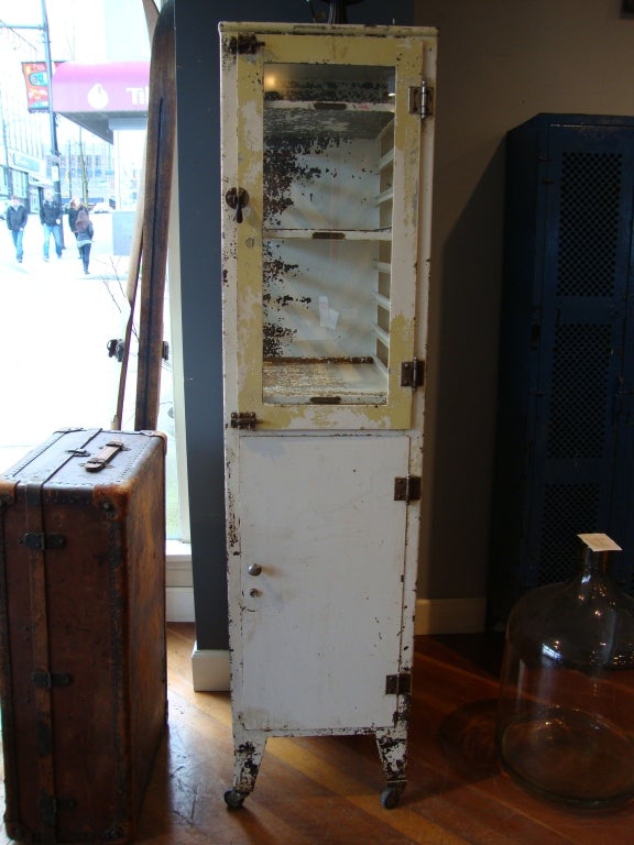 Medical cabinet with multiple  shelves , closed bottom storage and glass panels in original dry surface. Found in Detroit
