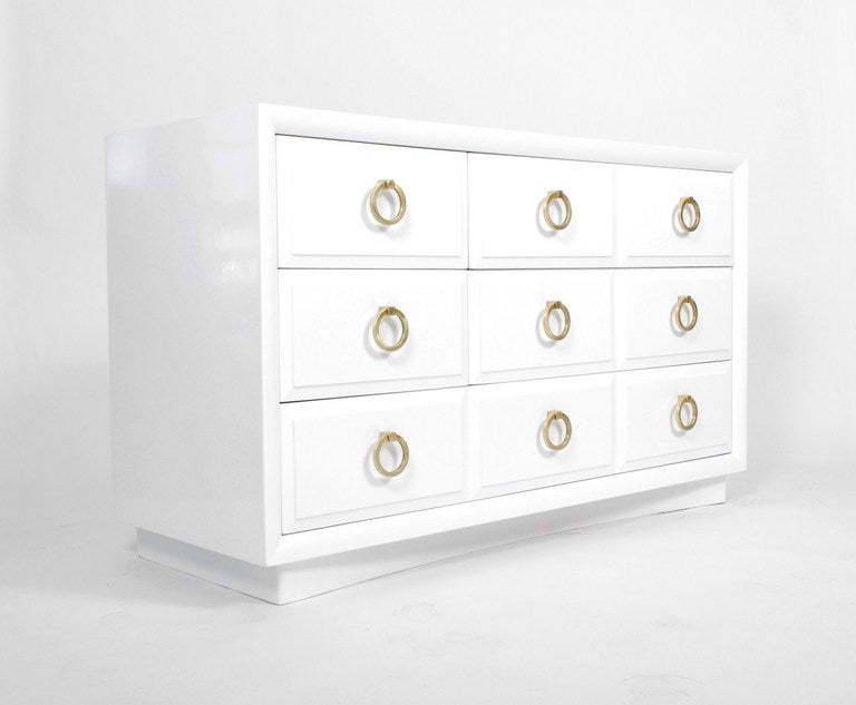Elegant dresser/chest of drawers designed by T. H. Robsjohn Gibbings for Widdicomb. This five (5) drawer dresser has been beautifully refinished in glossy white accented by the original matte brass ring pulls. Marked. There is also a smaller,