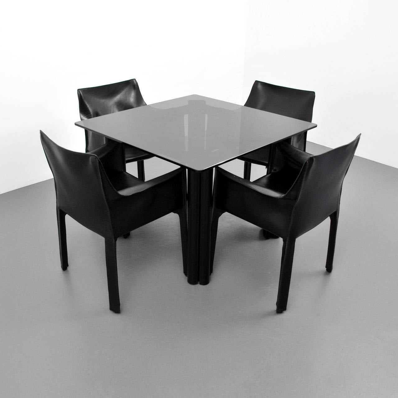 Set of four leather arm chairs by Mario Bellini. Tinted glass and leather wrapped base dining/game table by Acerbis International. Cassina label to chairs.

Dimensions: 28