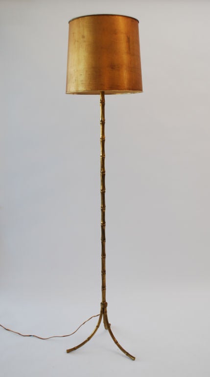 Fine floor lamp in the manner of Bagues. Elegant design with three legs and a polished brass body crafted in the shape of a bamboo culm, finished with a gold toned shade.

*Notes: There is no sales tax on this item if it is being shipped out of