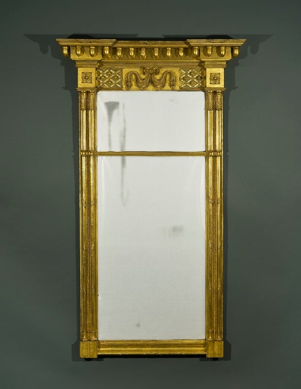 New York, circa 1815-1820.
Wood, gesso e dorato, con piastra a specchio.
Altezza 75 1/2, larghezza 44 1/8 (al cornicione), profondità 8 1/2 (al cornicione).

Condizioni: Alcuni restauri alle parti intagliate e gessate e alcuni restauri alla