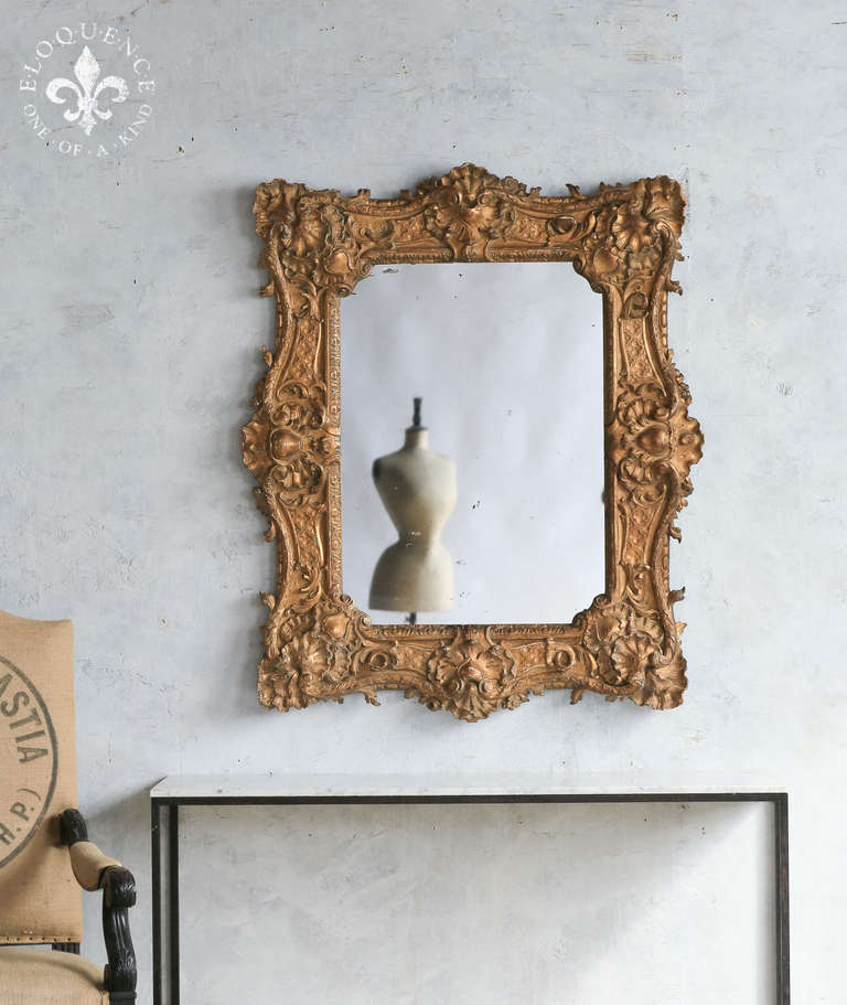 Phenomenal and stunning Antique Baroque mirror from France in a faded deep gilt. Absolutely incredibly decadent carvings engulf the frame, creating a real show stopper. Symmetry allows you to hang this piece either vertically or horizontally, giving