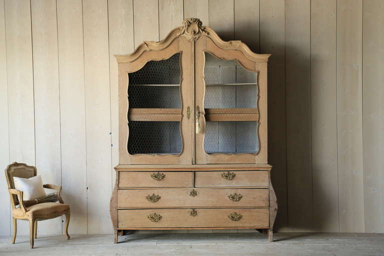 Phenomenal stripped antique Belgian linen press with a gorgeous voluptuous shape and hand-carved crest. We've added chicken wire to the top doors, and there are plenty of large drawers as well. Fantastic original hardware adds the perfect amount of