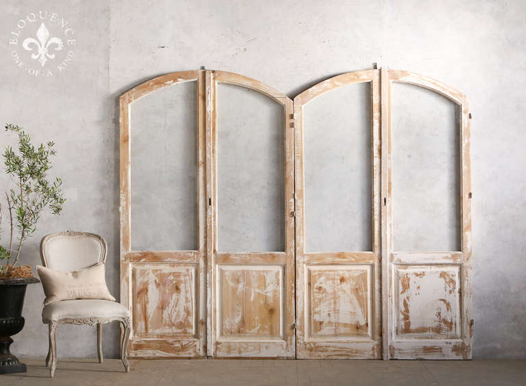 Fantastic pair of vintage arched doors in a bare wood finish with distressed original white paint. These would make a beautiful room divider for a space that needs a bit of vintage character. Can also be used as a functional door set, however frame