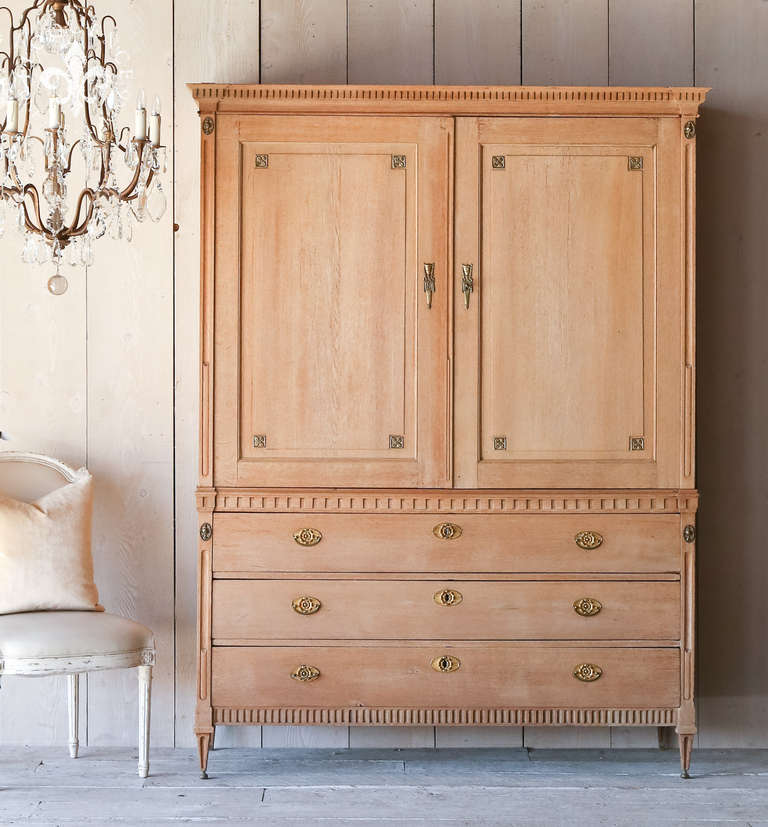 Absolutely stunning antique cabinet from Holland. In a clean and straight neoclassical style with delicately tapered legs with small brass feet and hardware details. Finely carved fluted detailing along edges.  Gorgeously bleached and stripped for a