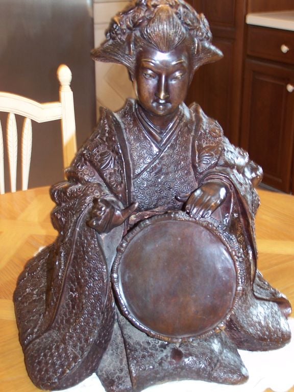Highly detailed bronze of a female Japanese musician playing a percussion instrument.