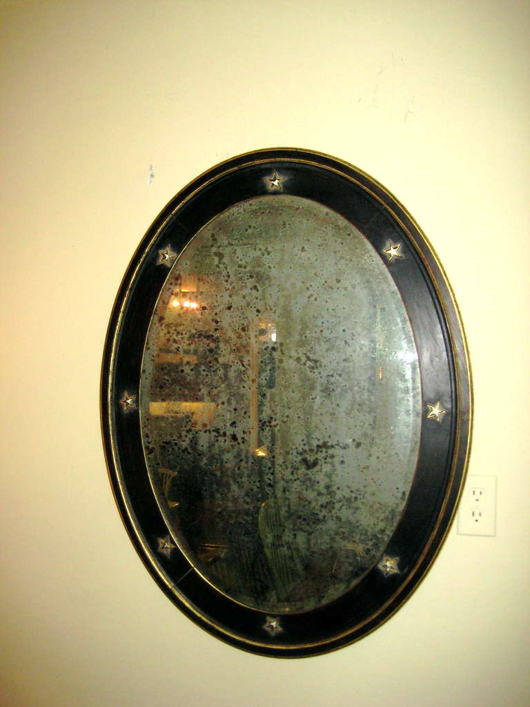 Black and gold painted oval convex mirror with star motif.