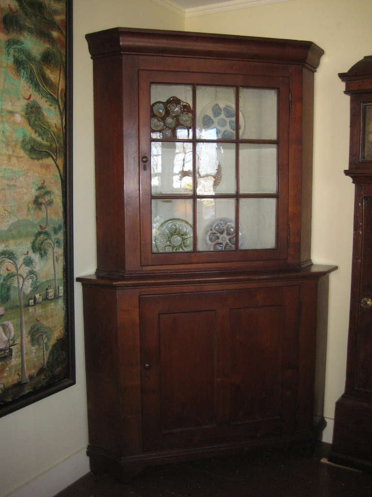 Early American pine corner cupboard with painted interior and glazed glass in door.