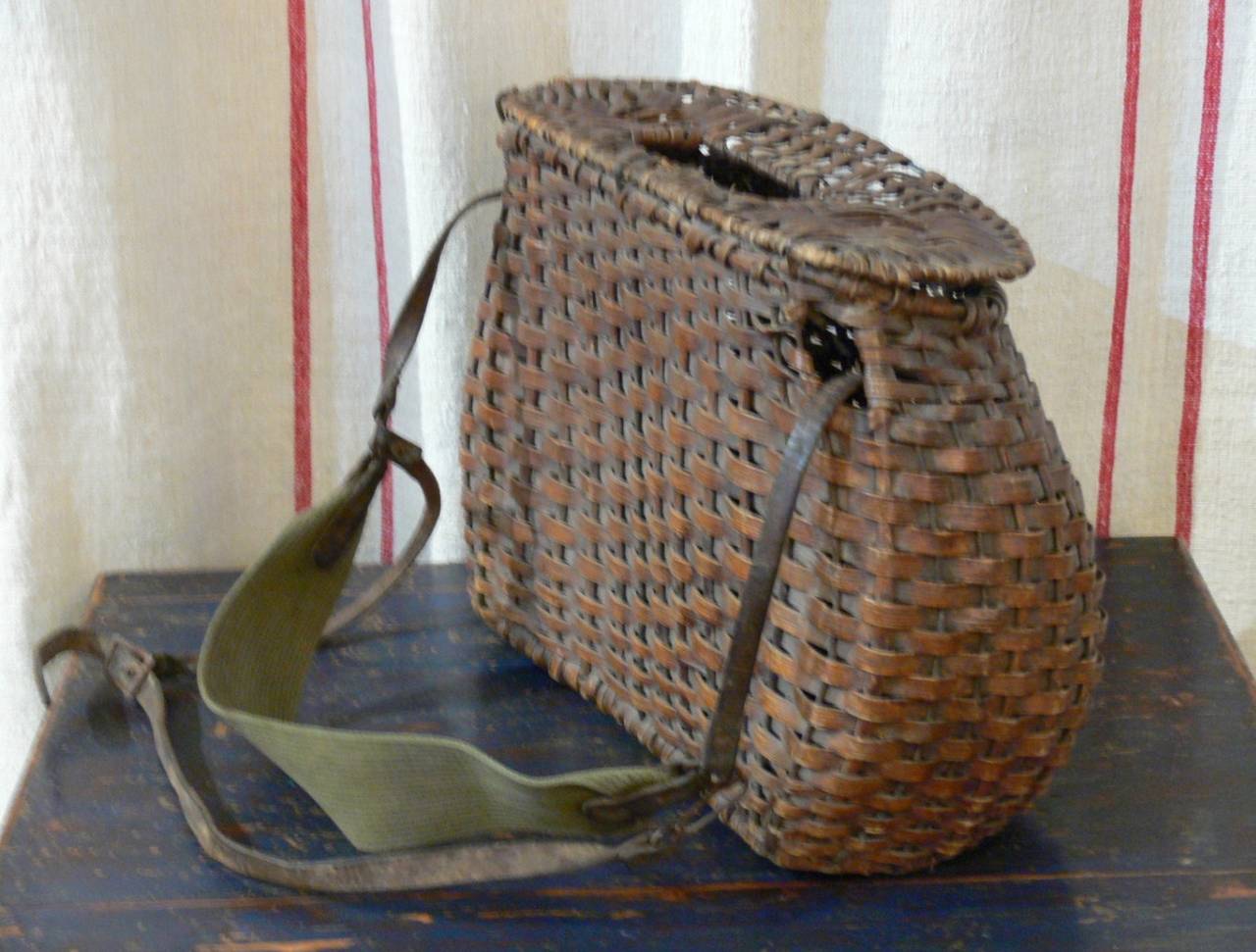 Large wicker fishing creel with buttock shape. Strap of leather and cotton.
