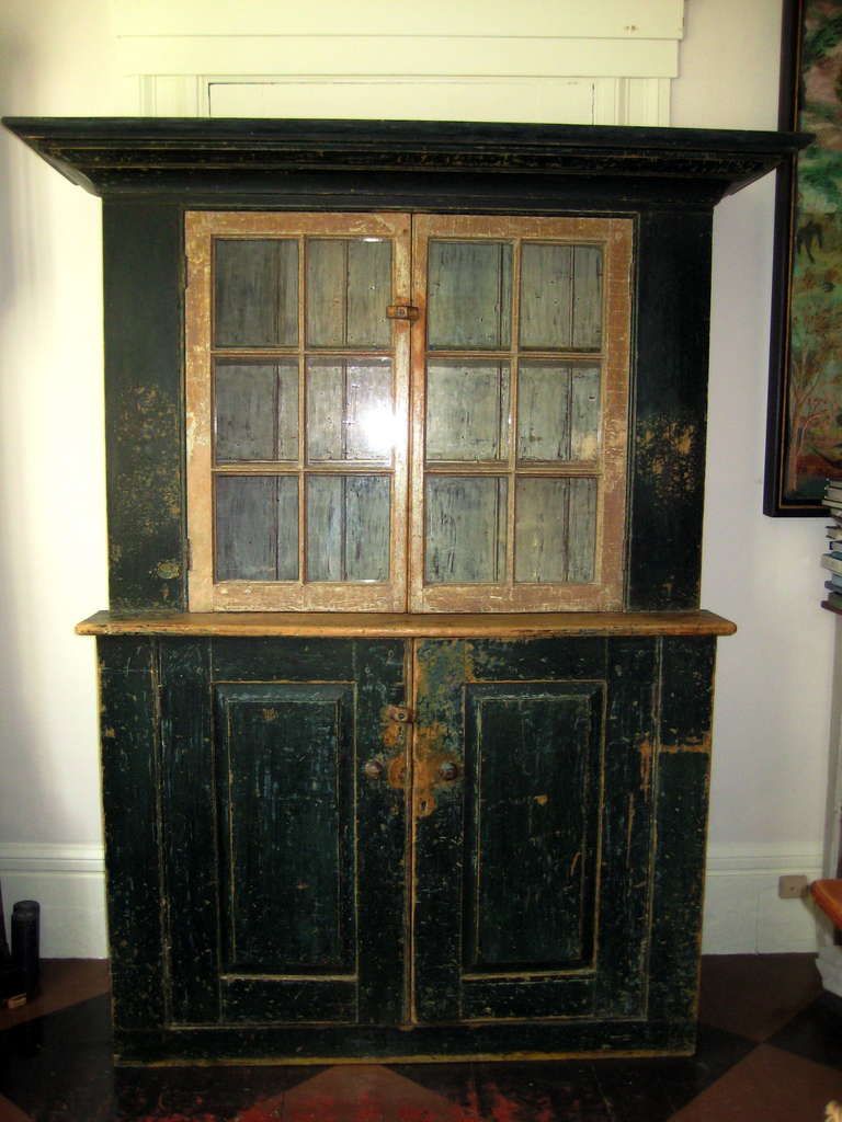 19th century Pine glazed step-back cupboard in original contrasting green and white paints, paneled doors.  Upper section with two shelves with plate rails.  Lower with single shelf.  Cream painted interior throughout.