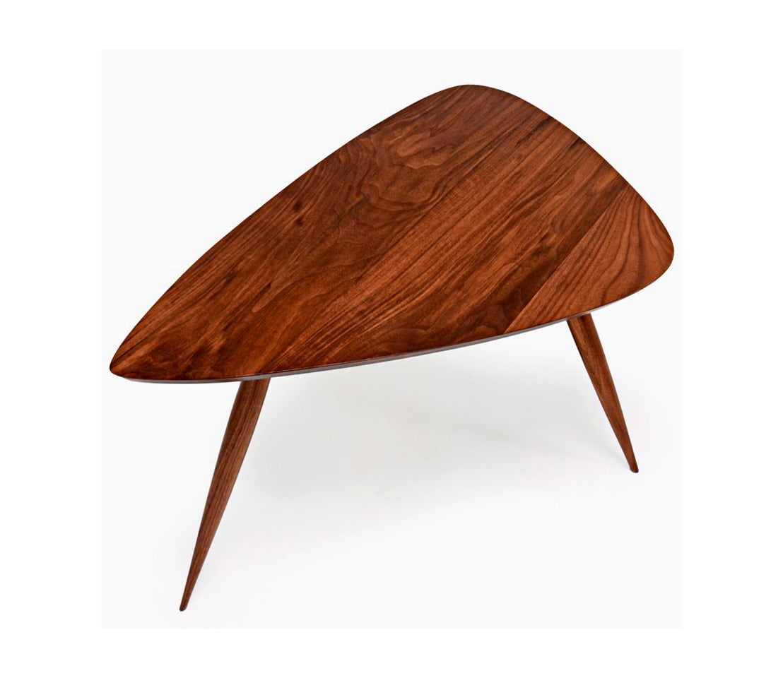 A sculpted tripod triangular tables in American walnut studio crafted by Phillip Lloyd Powell in his New Hope Studio, circa 1960s.
The tabletop is supported by spindle and tapered legs and display expressive grains. Rounded edges exhibit a subtle