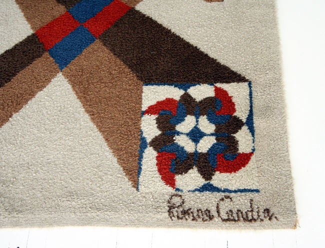 Wool area rug by French designer Pierre Cardin. Beige background with brown and chocolate geometrical design with red and blue accent colors. Signed on the lower right corner Pierre Cardin.