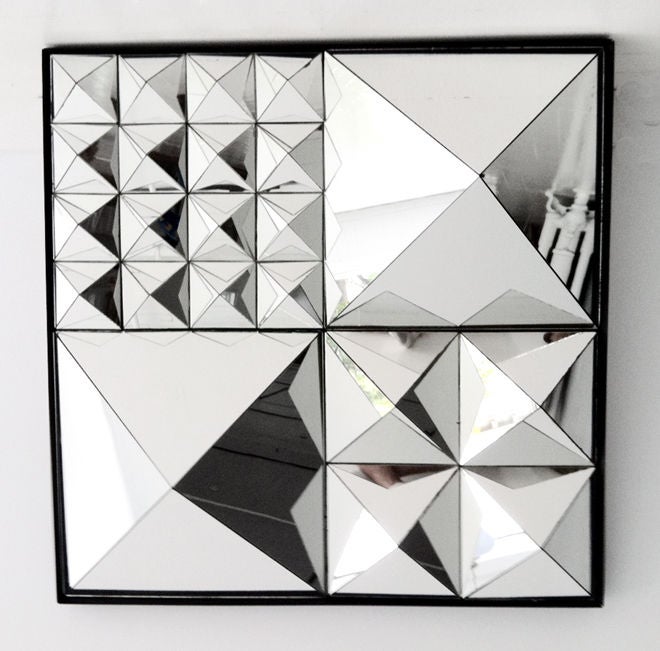 The sculptured wall mirror is composed of four contrasting panels of various sizes of pyramid shapes, framed in a likely later black wood frame for hanging. This design, used by Verner Panton in the decoration of his own residence, was produced in a