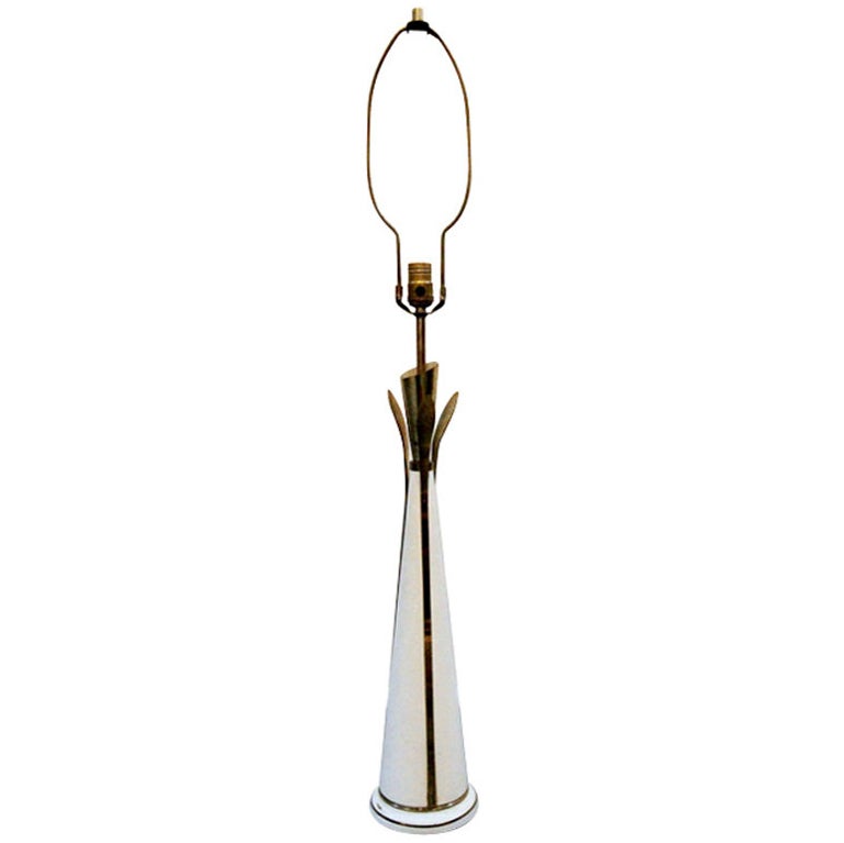 An artsy mid century lamp in white enameled metal contrasted with brass stripes and petals, stands an impressive 41.5 inches high. With fabric shade and brass finial.