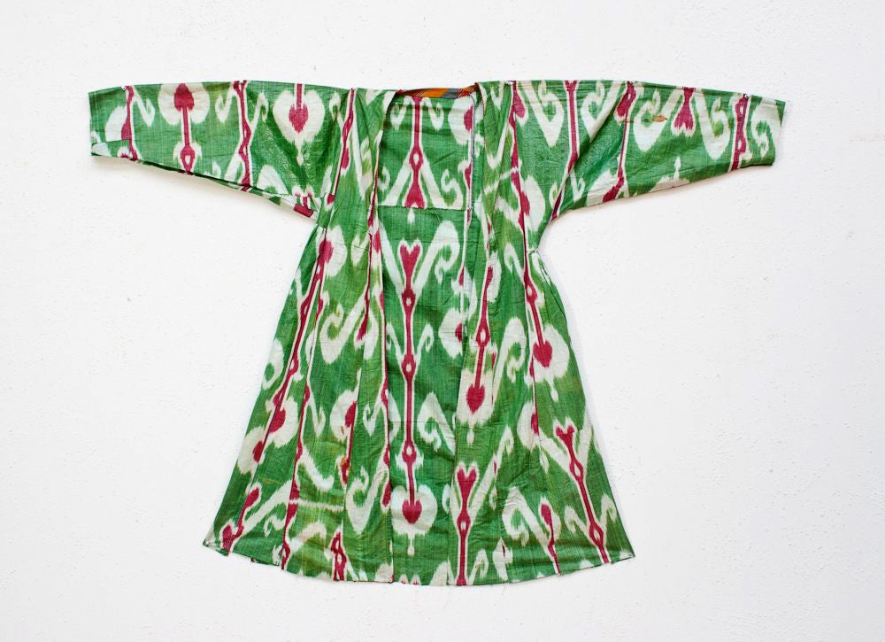 A beautiful central Asian Kaftan made from woven ikat pattern silk. Bold patterns throughout with white and dark red on green background. No lining. Collected in Uzbekistan. Originally made for local market.