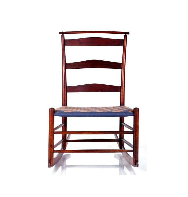 A Shaker rocker chair constructed with stained Maple. It features a ladder back, a shawl bar on top and webbed seat. Branded #4. Period piece from early 20th Century. Likely made in Mount Lebanon Shaker Community in New York. Simple and beautiful
