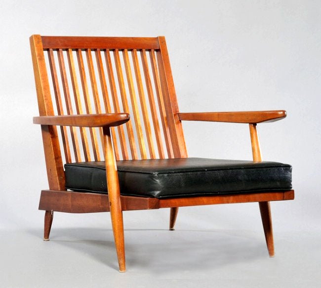 Lounge chair made by George Nakashima from New Hope Studio. Circa 1954. Back rest with twelve spindles, shaped armrests, loose cushion seats covered in black leather likely later. Provenance: From the family who commissioned the work in the