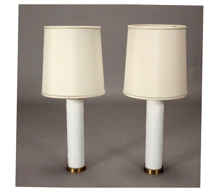 Pair of large white ceramic table lamps with brass base and fitting. Designed by Bjorn Wiinblad for Rosenthal Studio Line. Original shades. The white ceramic column is richly decorated with white on white embossed floral pattern, great detailed and