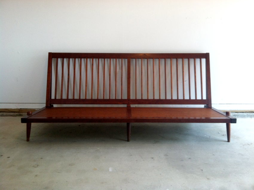 An early walnut sofa studio crafted by George Nakashima circa 1963. Simplistic armless form with squared spindled back and legs. The construction of the front legs were slightly unusual with its protruding end and visible dowels. With upholstered