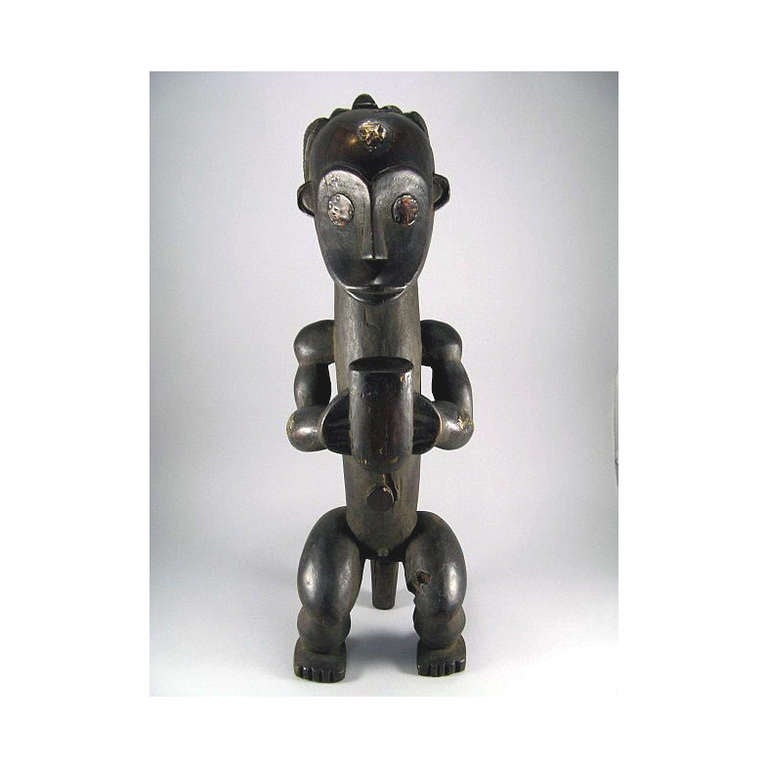 Standing 28 inches tall, this statue is of considerably stylized proportion and it impresses the viewers with a tranquilizing stance and meditative and facial expression. With a cylindrical neck that simply extends into the chest and torso, the