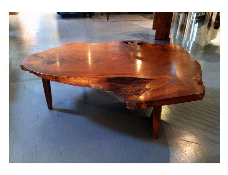 A rare coffee table custom-crafted by George Nakashima in his New Hope Studio circa 1977. It features an impressive thick American black walnut plank top with free edges all around, beautiful grains and sap holes and edges. Its contoured shape is