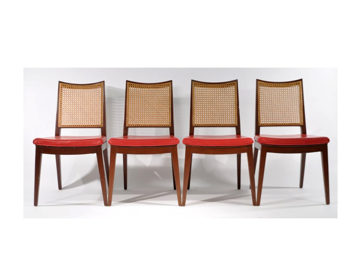 A nice set of four walnut side chairs by Edward Wormley for Dunbar. Leather seats with slightly curved caned back. Simple and elegant form with a Japanese sensibility. They retain Dunbar brass tags underneath.
