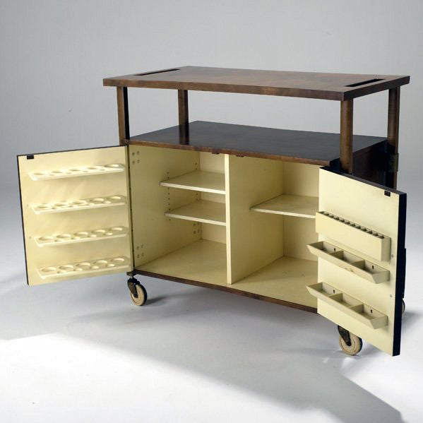 An awesome bar cart on castors by Harold Schwartz. This bar / serving cart circa 1950s was constructed with Quilted burl, stained birch with brass hardware and accent. The lacquered wood interior is fitted with shelves and bottle cup holders on the