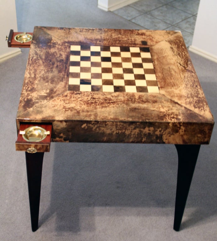 A great set of game table and four chairs by Italian designer Aldo Tura. It is quite unusual to have an original set together like this. The top of the game table is covered with goat skin parchment and an inlaid chess board/ Supported by four