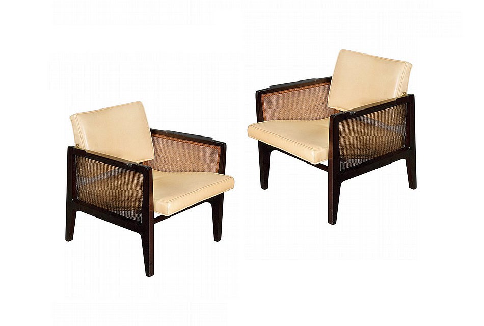 A pair of great looking lounge chairs with arm designed by Edward Wormley for Dunbar. Constructed with solid ebonized Mahogany and upholstered in a beige color leather, these chairs features shaped arm with caned side panels and provide great