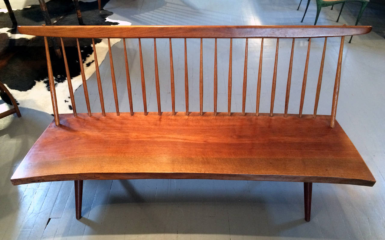 One of the iconic design by American woodworker George Nakashima, this bench was custom-made for a client in 1960 using walnut slab with spindle back and free front edge. The front edge also displays various worm trails, a natural occurrence in the