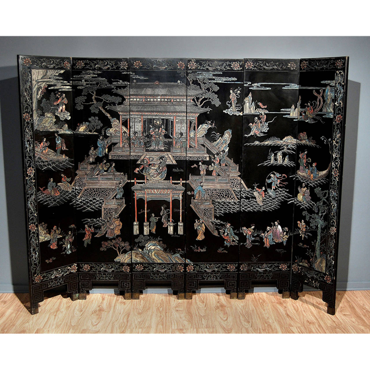 A Six Panel Black Lacquer Cormorandel Screen with Polychrome Decoration Depicting An Empress in A Seaside Pavillion Surrounded by Dieties and Attendents Carrying Auspicious Objects. Chinese, Circa Late 19th Early 20th Century.