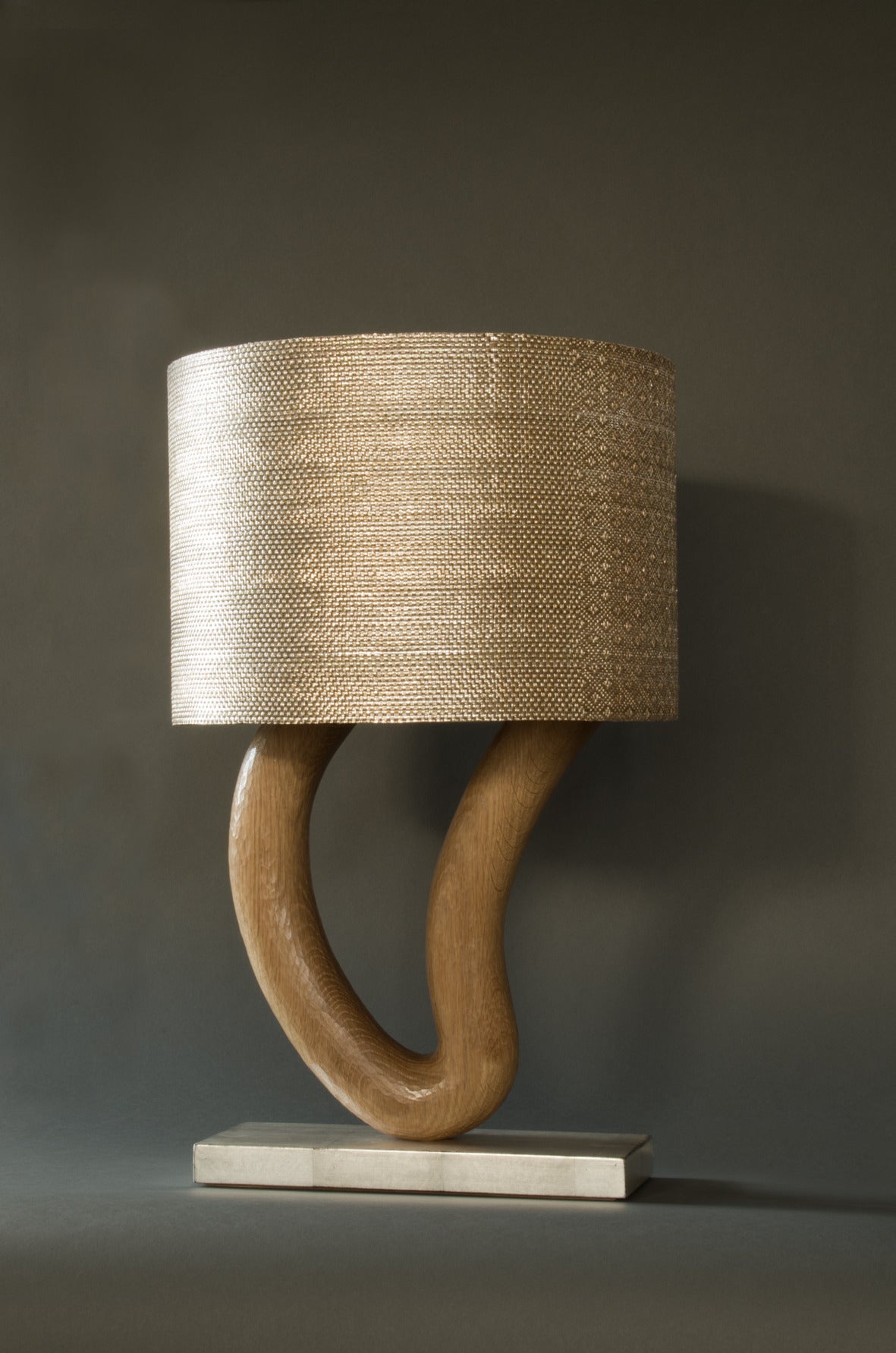Table lamp with base in silver-leaf patinated steel and hand-sculpted and waxed oak. Shade in silver copper polyamide.

Unique piece. 
2015. 

This couple combine their respective talents in ingenious textile use and Greco-Roman architecture to