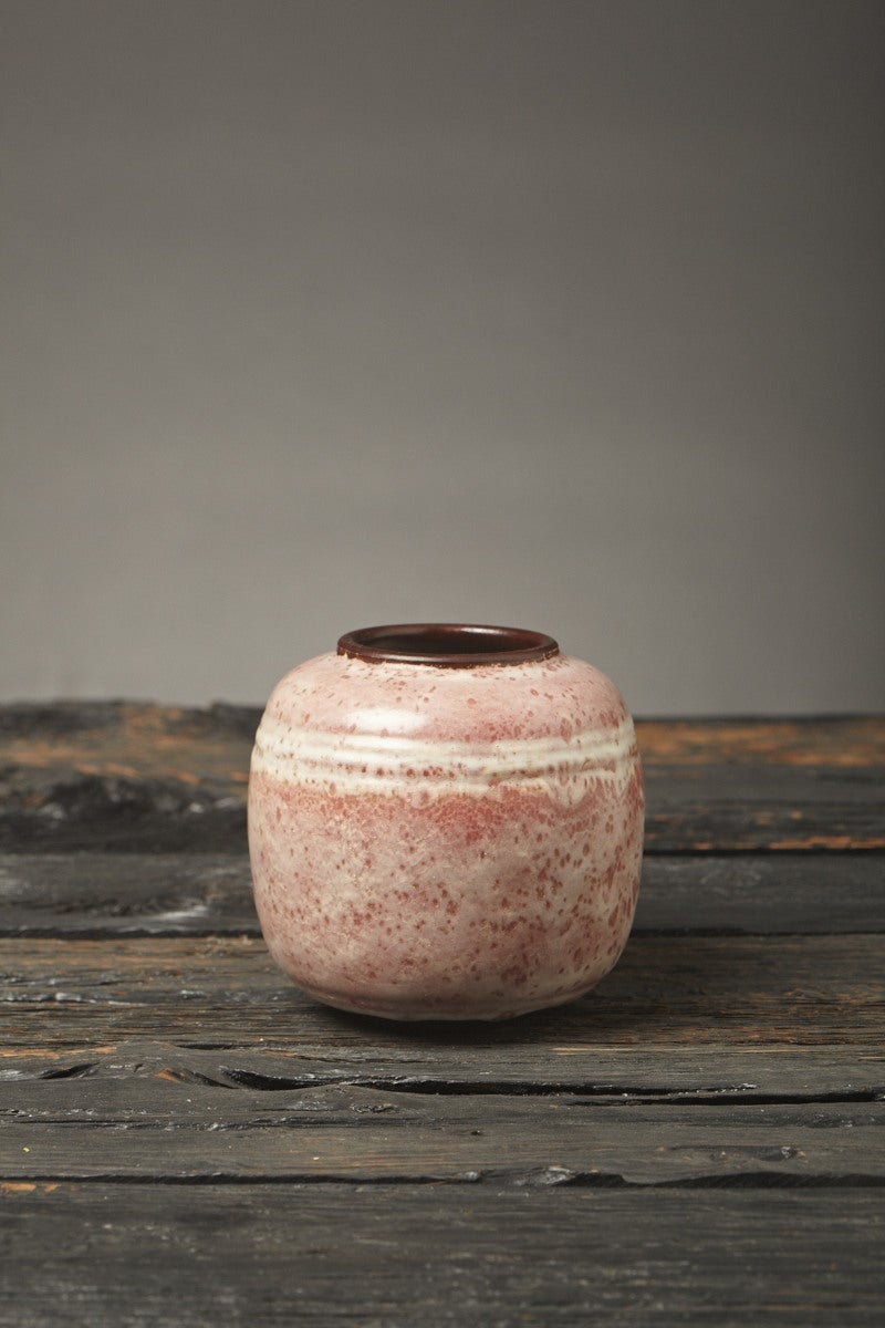 The globular form and distinctive mauve matte glaze decoration of this stoneware vase, work together to create the effect of heavily cratered planetary terrain. At the same time, the distorted clusters of white flecks create the appearance of a