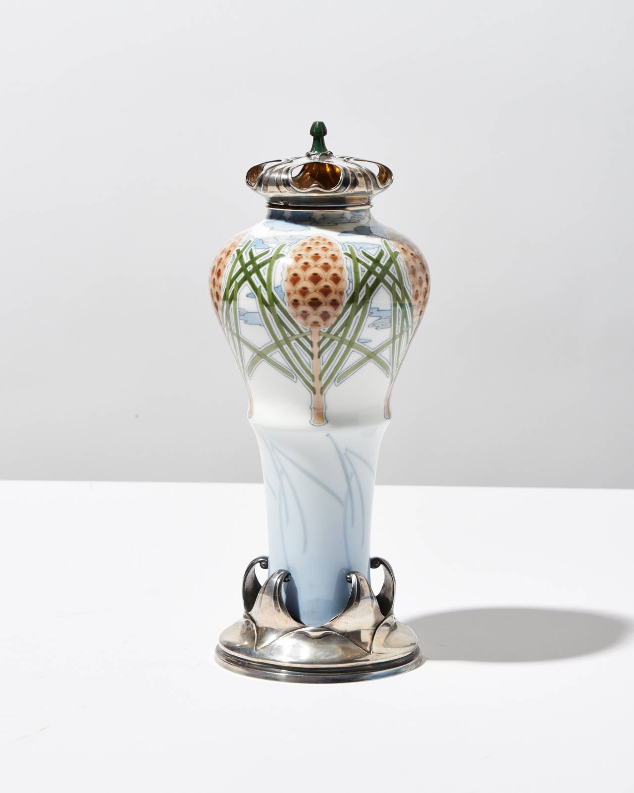 This porcelain vase was produced in 1897 by Sèvres porcelain manufactory. With paintings by Henri Lasserre depicting a winter landscape, the white porcelain base is carefully painted with vegetative imagery in strong, geometric patterns. The vase