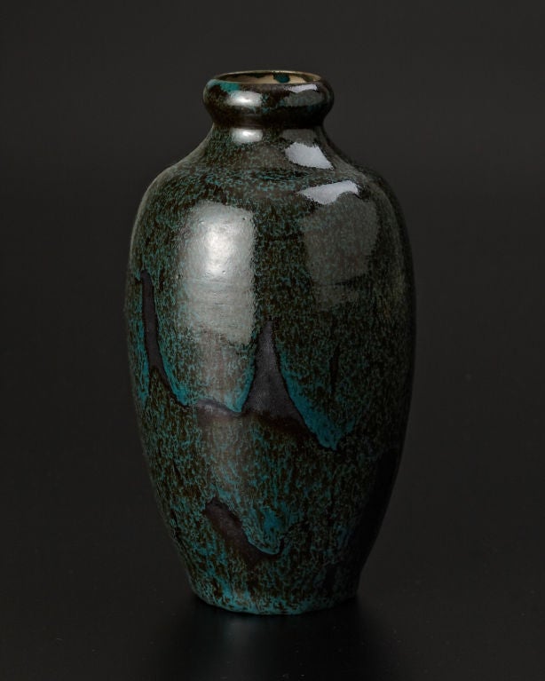 This elegant hand-thrown Japonist vase, graceful and simple in form, is decorated with a high-fired, mottled glaze in shades of dark green, with flecks of black, evoking the surface of an igneous rock. Marks: Inscribed artist's signature, artist's