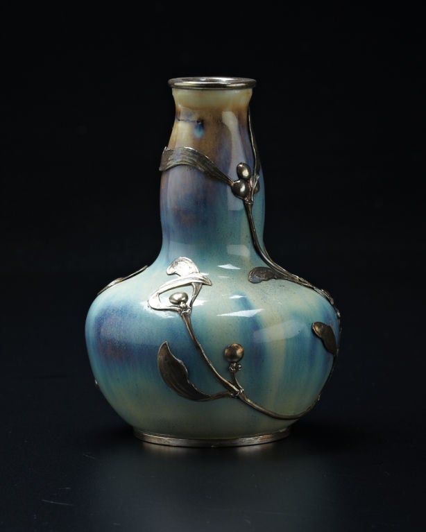 This stunning petite stoneware vase is richly decorated in icy blue glazes with streaks of beige and an exquisite metal mount in the form of naturalistic mistletoe. The mount was created by Lucien Gaillard, one of the most celebrated Art Nouveau