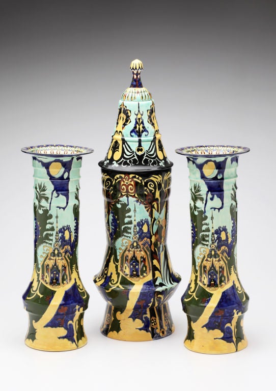 T.A.C. Colenbrander for Rozenburg. This enchanted garniture, with its architectural reference to an Indonesian pagoda, depicts a folkloric scene of a temple nestled in a dark forest teeming with animistic shapes and colors. On the covered vase, the