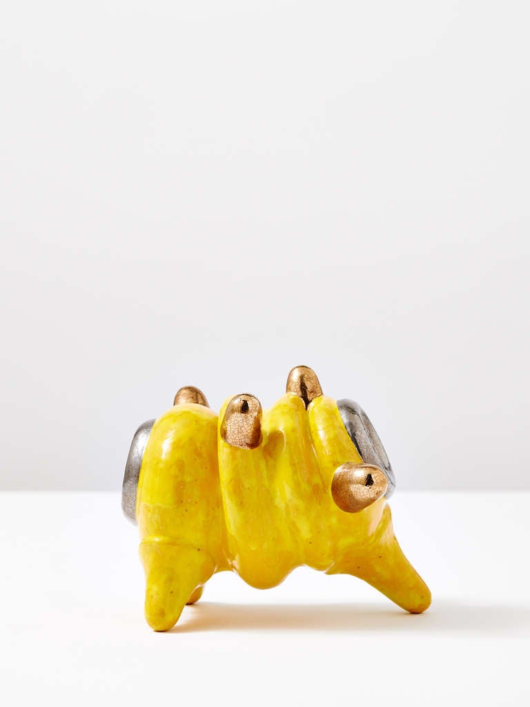 Yellow standing object with Platin by Michael Geertsen.

Geertsen is known for sleek ceramic works with alien-like sculptural bodies, and stacked sculptures of utilitarian objects like plates and cups. His whimsical and animated forms are executed