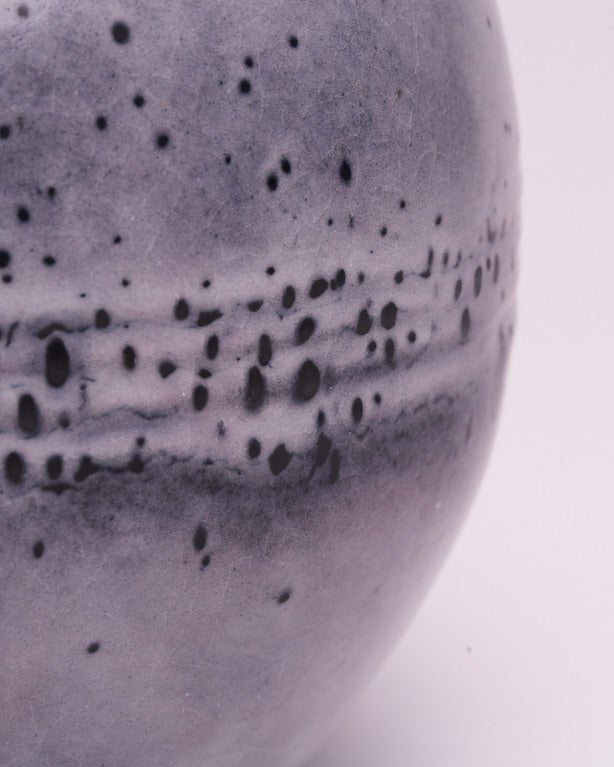 The globular form and distinctive pearly matte glaze decoration of this stoneware vase, work together to create the effect of heavily cratered moon terrain. At the same time, the distorted clusters of dark flecks create the appearance of a dense