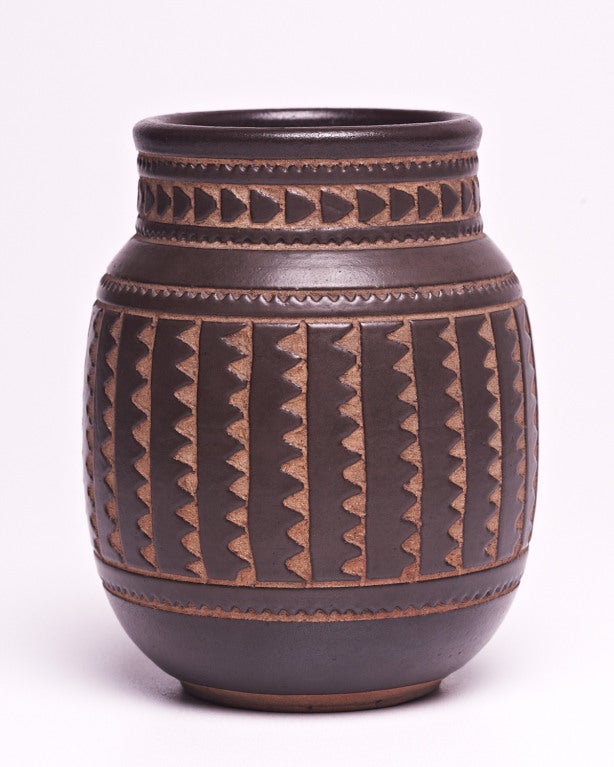 A fine hand thrown stoneware vase by Emile Lenoble. The elegantly proportioned body is decorated with a broad central band of incised undulating motifs, running vertically around the form. A similarly jagged geometric design encircles the neck. The