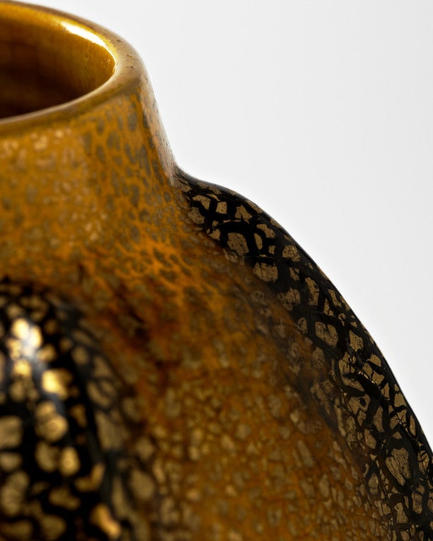 This extraordinary vase calls to mind some sort of exotic reptilian creature with glistening gold-tinged scales. The raised, spine-like protrusions running vertically along the length of the ovoid form are like impressive dorsal crests running from